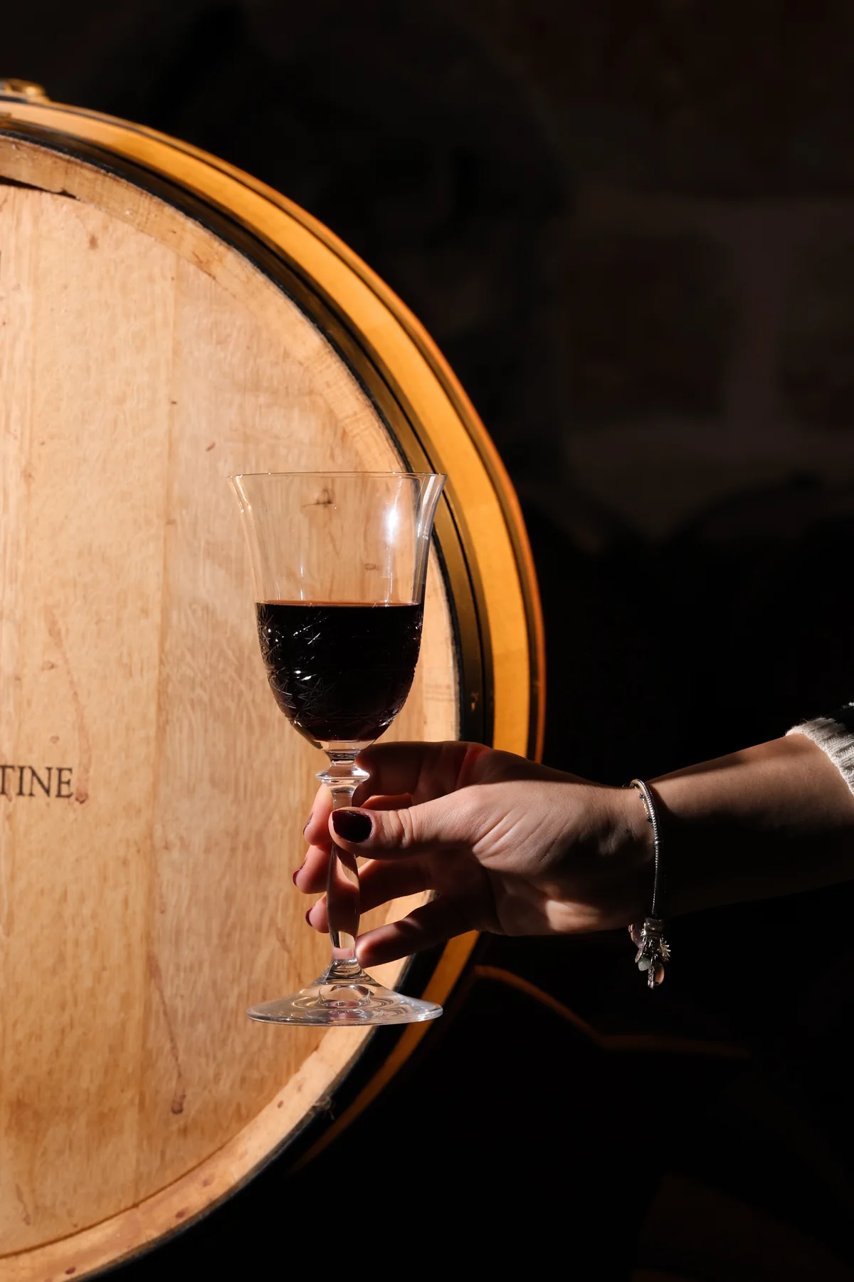A glass of red wine held against a Château Florentine barrel