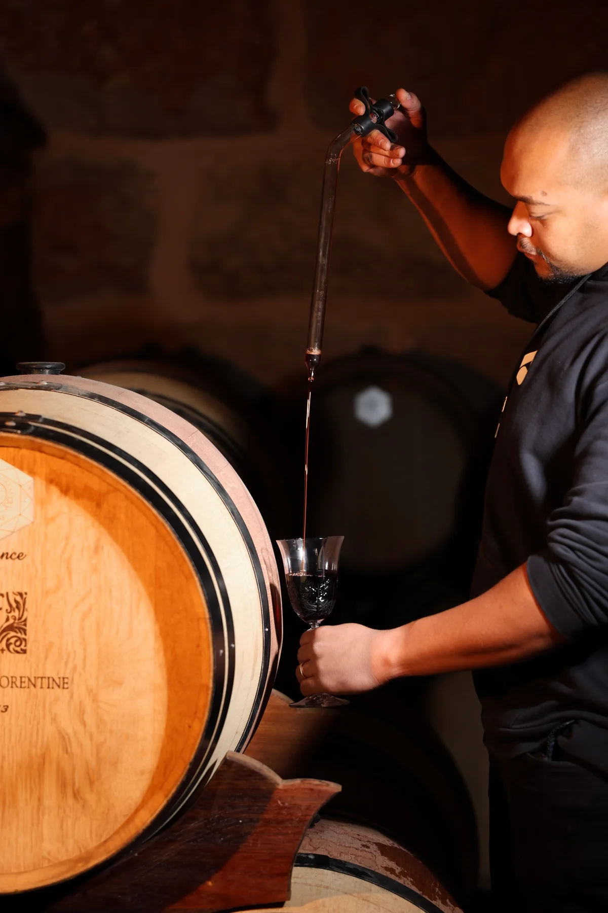 Drawing a barrel sample with a wine thief in the cellar